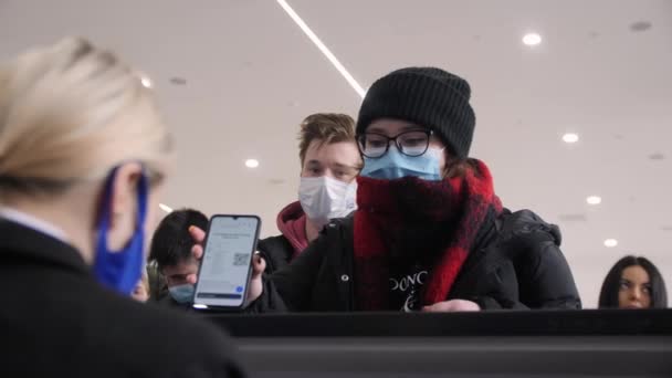 Женщина в одноразовой маске показывает цифровой билет за стойкой — стоковое видео