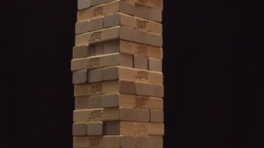 İnsan eli, karanlık odada gri masada Jenga kulesini kırar.