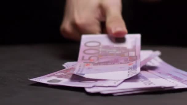 La mano del hombre pone gran billete de euro en la pila en la mesa negra — Vídeos de Stock