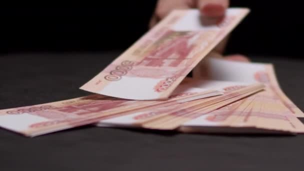 Mão homem coloca conta rublo russo em pilha de dinheiro na mesa — Vídeo de Stock