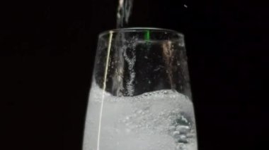 Siyah arka planda zarif flüt bardaklarına şampanya dolduruyorum.