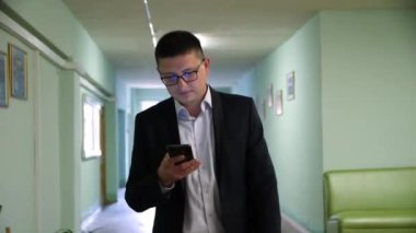 Adam ofis binasının koridorunda yürürken çağrıya cevap veriyor.