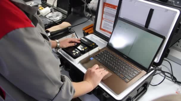 Engenheiro trabalha no laptop e pressiona as teclas no painel de controle — Vídeo de Stock