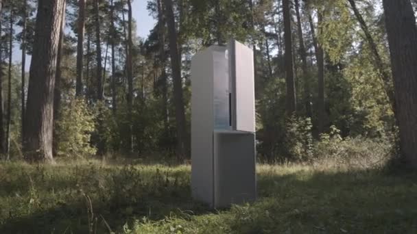 Дружелюбний холодильник стоїть на зеленій галявині в лісі. — стокове відео