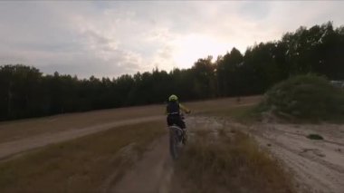 Motosikletli taşra yolu boyunca motosiklet sürüyor.