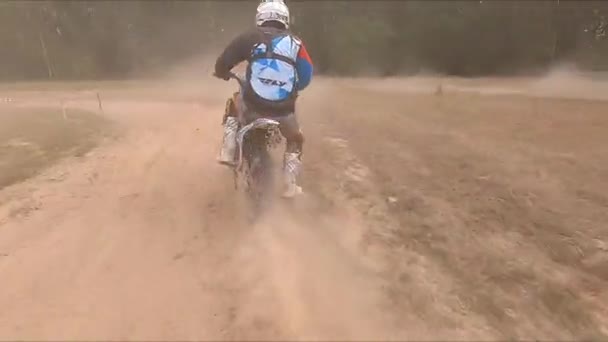 Homem monta moto ao longo da estrada rural empoeirada em grande campo — Vídeo de Stock