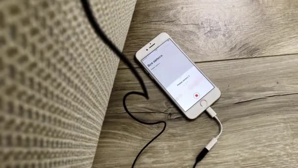 Charging cellphone with open audio record appliance on table — Stock Video