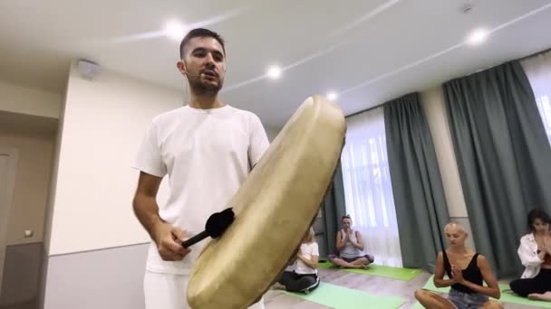 Man plays ethnic tambourine conducting yoga training in gym — Stock Video