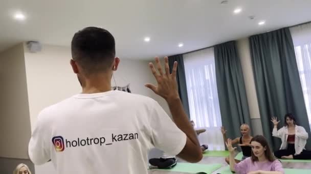 Homme explique asana à la formation des participants en studio de lumière — Video