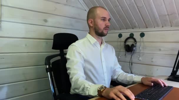 Gerente trabaja en el ordenador sentado en la mesa de madera en casa — Vídeos de Stock