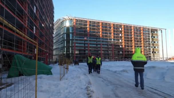 Constructores caminan a lo largo de la carretera nevada en el sitio de construcción grande — Vídeos de Stock