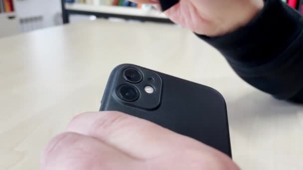 Cameraman limpa a lente da câmera do telefone com ferramenta na mesa — Vídeo de Stock