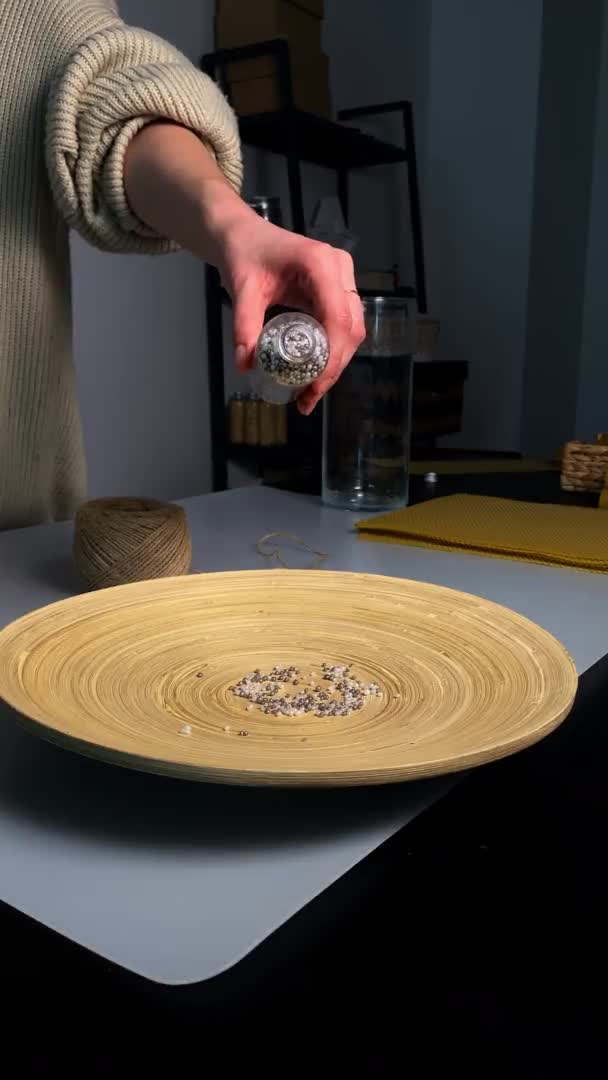 Frau gießt kleine Perlen aus Glasflasche auf Keramikteller — Stockvideo