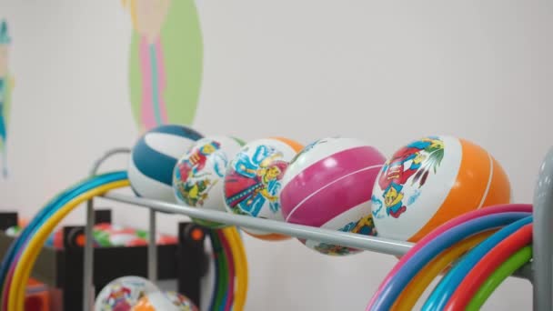 Balls and hula hoops on rack in hall for children gymnastics — Stockvideo