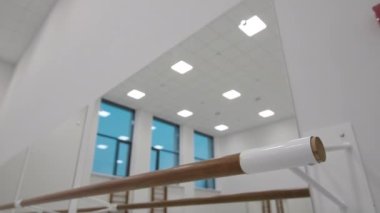 Wooden bar near large mirror in brightly lit dance class