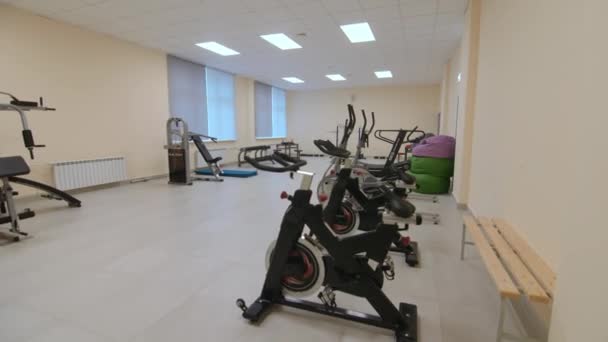 Row of machines stands by wall in brightly lit spacious gym — Stockvideo