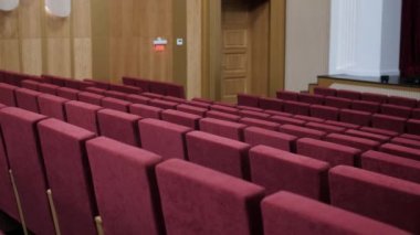 Rows of red armchairs for spectators in theater auditorium