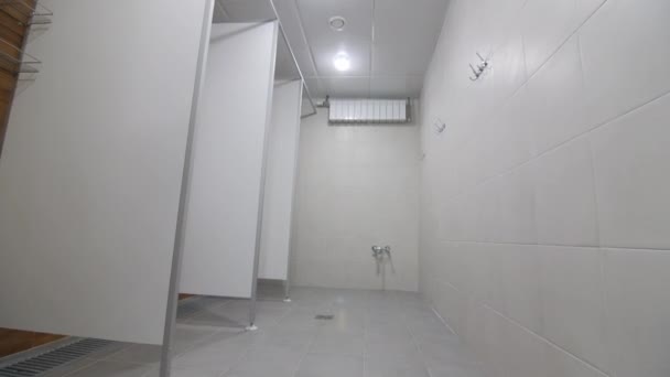 Rows of cabins separated by white walls in empty shower room — Stok video