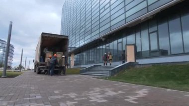 Movers carry boxes into office building at construction site