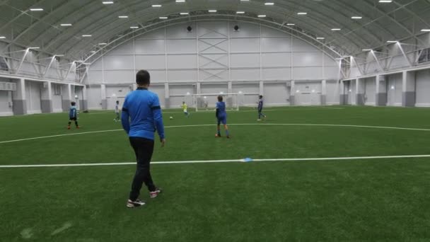 Children play football with trainer on indoor field — Stok video