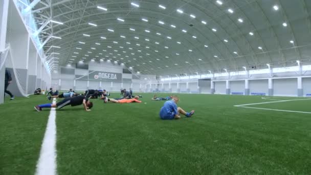 Children do workout before football game on indoor field — 图库视频影像