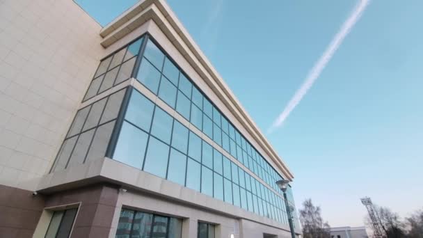 Movimiento más allá de la pista de condensación del edificio en cielo azul claro — Vídeo de stock