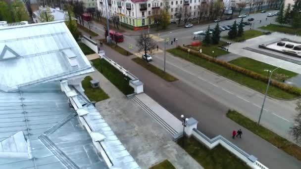 Bus rouge conduit le long de la rue devant le bâtiment et grand parc — Video