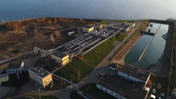 Estação de tratamento de esgoto com grande piscina na margem do rio ao entardecer — Vídeo de Stock