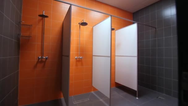 Cabinas de ducha vacías con equipo nuevo y pared de azulejos naranja — Vídeo de stock