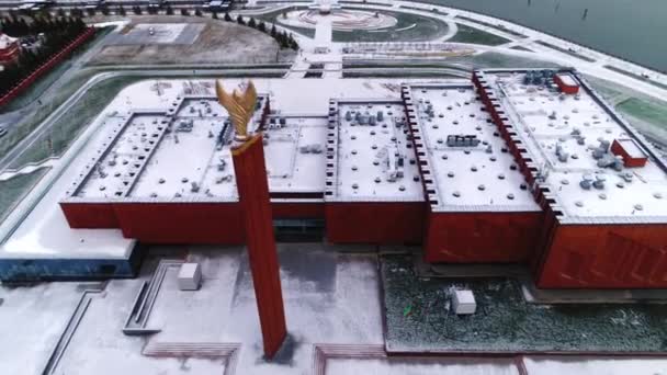 Estela vermelha alta com tocha olímpica na frente do complexo esportivo — Vídeo de Stock