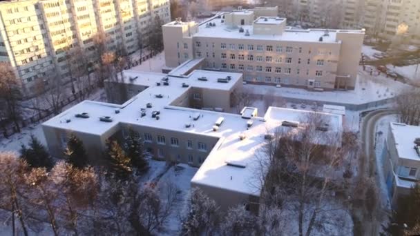 Здание школы с заснеженной плоской крышей среди жилых районов — стоковое видео