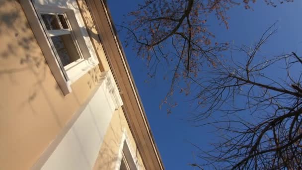 Edificio antiguo con fachada amarilla y ramas de árboles desnudos — Vídeos de Stock