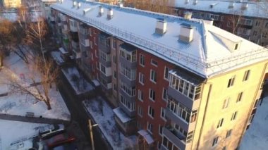 Gün batımında kar kaplı çatısı olan bir apartman.