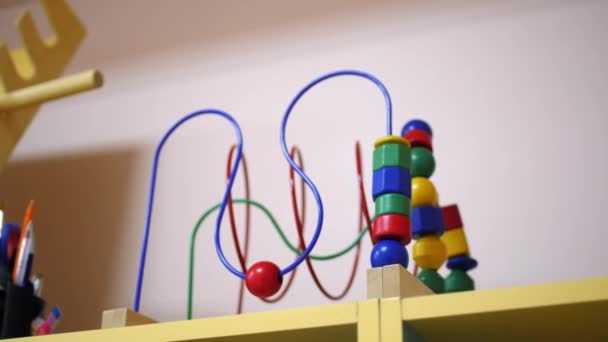Bead maze development toy on shelf in play room of daycare — Stock Video