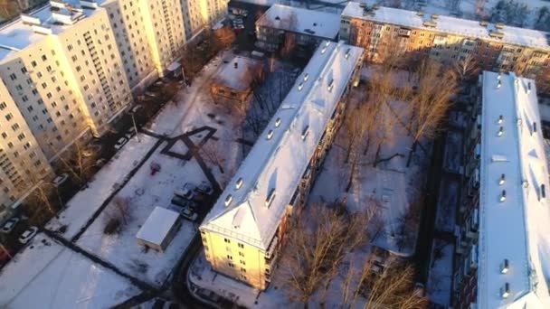 Diferite clădiri cu acoperișuri de zăpadă și curte cu copaci goi — Videoclip de stoc