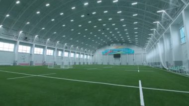 Spor kompleksindeki büyük kapalı futbol sahası boyunca hareket