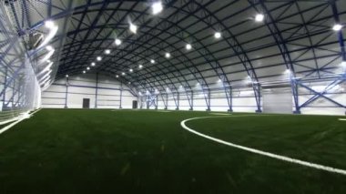 Yarı dairesel çatı altında yemyeşil çimlerle kaplı futbol sahası