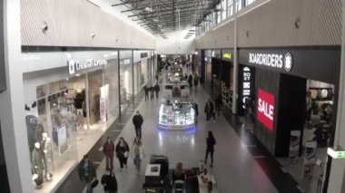 Müşteriler koridorlarda tezgahlarla yürür pencereler gösterir