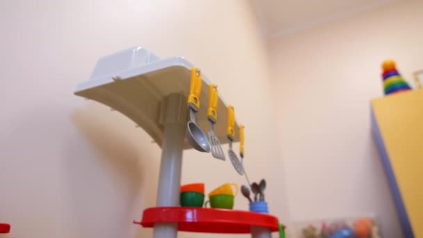 Zabawka kuchnia z drobnymi naczyniami w pobliżu białej ściany w pokoju zabaw — Wideo stockowe
