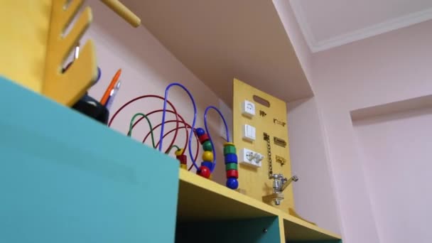 Laberinto de cuentas y tablero ocupado en el estante en la sala de juegos del jardín de infantes — Vídeos de Stock