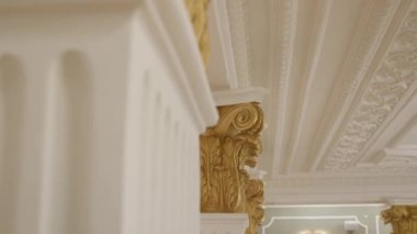 Koridorda altın dekorlu sütunlar ve güvenlik kamerası var.