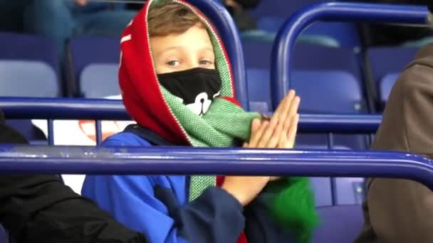 Tiener jongen met masker en sjaal wrijft handen bij hockey wedstrijd — Stockvideo
