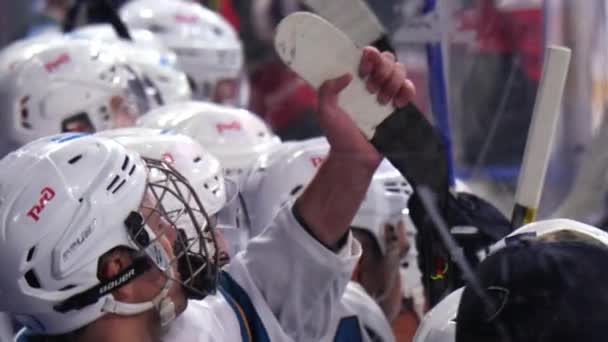 Hockey player checks stick sitting with colleagues near rink — Stock Video