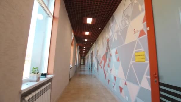 Длинный пустой коридор с дверями и окнами в спортивной школе — стоковое видео