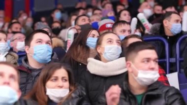 Maskeli kalabalık stadyumda hokey maçının keyfini çıkarıyor.