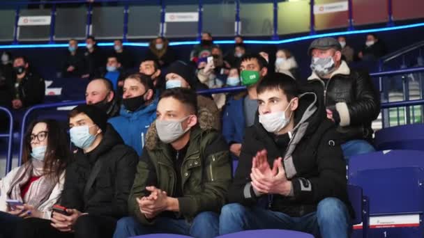Любители хоккея в масках смотрят интересный матч на стадионе — стоковое видео