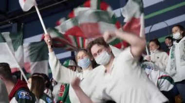 Mutlu genç adam hokeyde Tribünde arkadaşlarıyla dans ediyor.