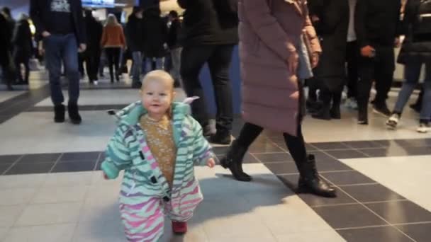 Schattig klein meisje in jumpsuit komt naar camera langs hal — Stockvideo