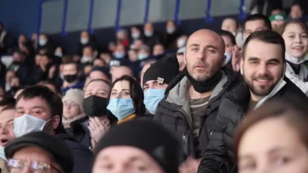 Mature breaded man with mask claps hands watching hockey — Stock Video