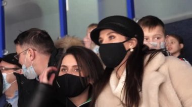 Tıbbi maskeli bir kadın hokey maçında arkadaşıyla konuşuyor.